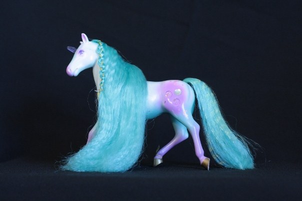Alexis; Body Color: White, Purple, and Turquois<br/>Hair Color: Turquois<br/>Horn Color: Purple <br/>Jewel Color: Very Very Pale Pink, Short Horn Version: Silver<br/>Brush: Pink<br/> Accessories: 2 Medium Purple Ribbons, 1 long gold elastic<br/>Notes: Front section of mane is braided two parts hair, one part gold elastic. Tail is braided and secured with gold elastic.