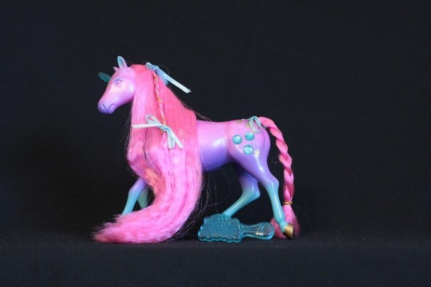 Jewel; Body Color: Pink, Purple, Turquois.<br/>Hair Color: Dark Pink<br/>Horn Color: Turquois <br/>Jewel Color: Turquois<br/>Brush: Turquois <br/> Accessories: 3 Turquois Ribbons, 1 long gold elastic<br/>Notes: small section of mane is braided two parts hair one part gold elastic, tail is braided secured with gold elastic. Body accented with gold hearts and dots.